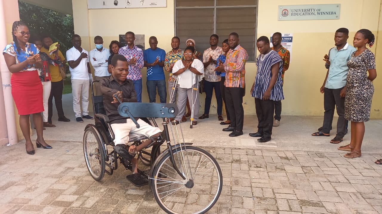 Mr. Bright Zinaneeba testing the custom-made tricycle donated to him in the presence of the donors 