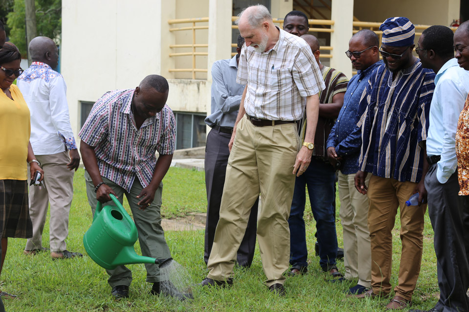 Mr. Gordon Donkoh-Halm watering the newly planted umbrella tree while Prof. Giles and UEW faculty members look on