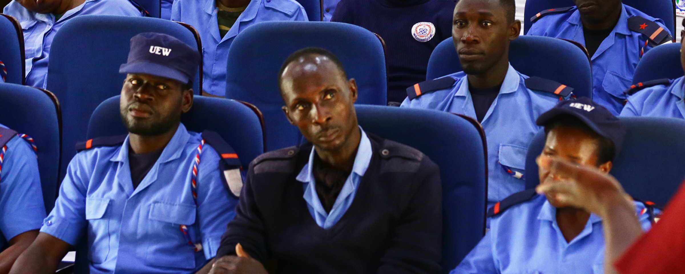 A photograph of university staff, including two security personnel, seated together in a workshop setting